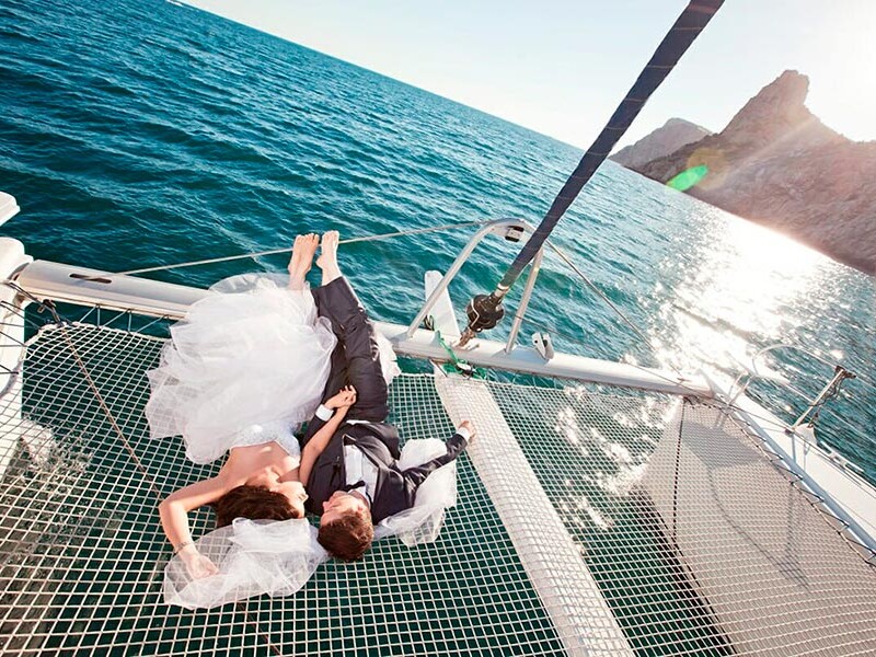Wedding couple lying down on catamaran net in Santorini