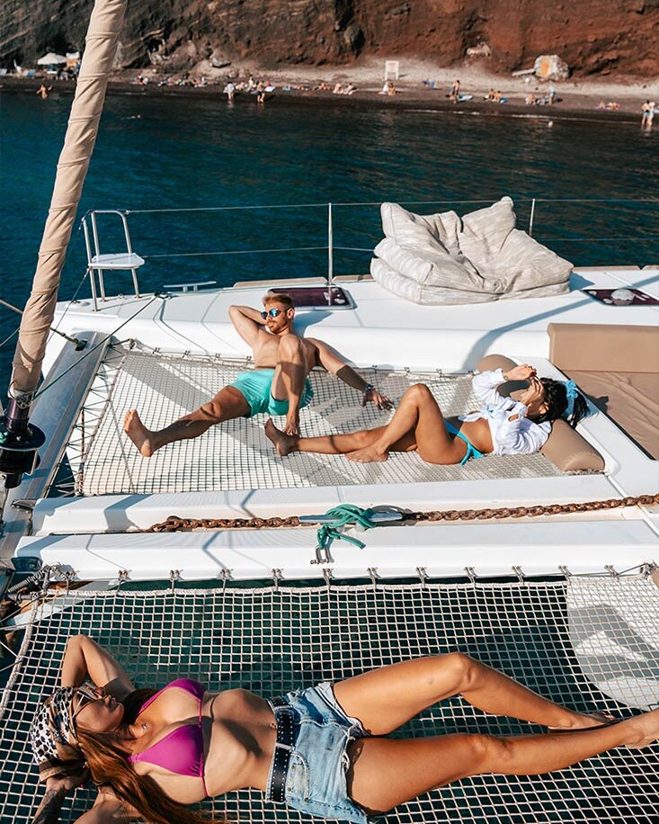 Group of friends sunbathing on Catamaran in Santorini