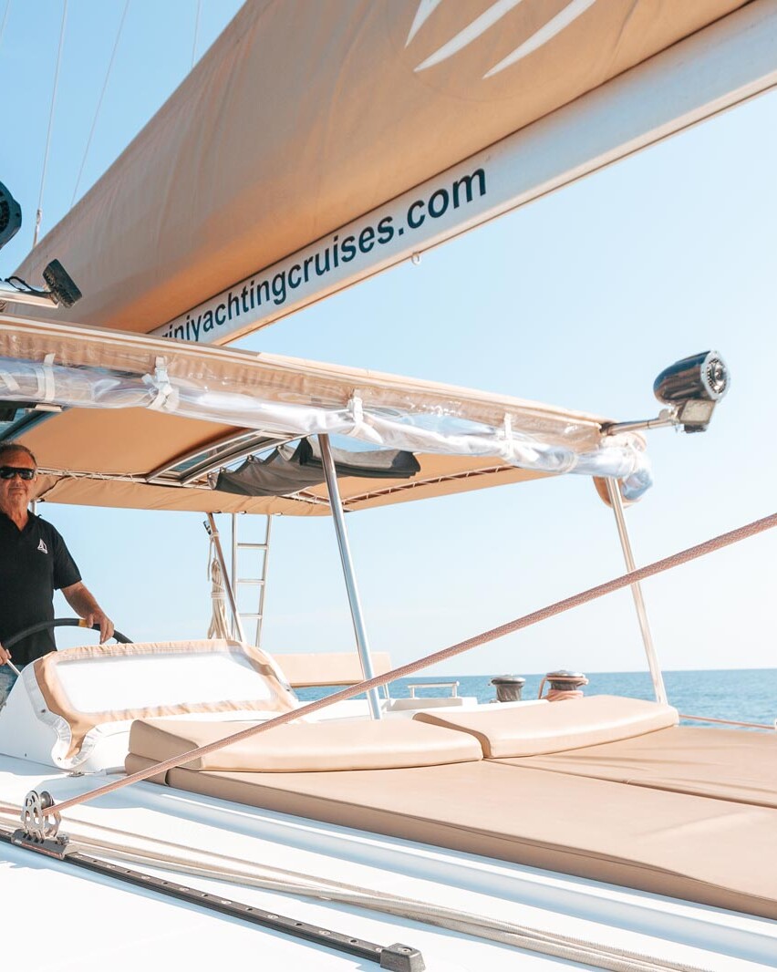 Catamaran skipper sailing a catamaran on Santorini Yachting Cruises