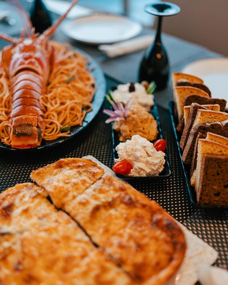 Close up of a dish of Musaka with food in background, on a table on a Catamaran in Santorini
