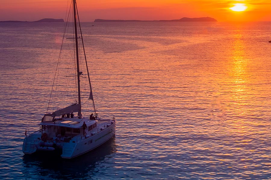Catamaran sailing in the Santorini sunset with bright red sky