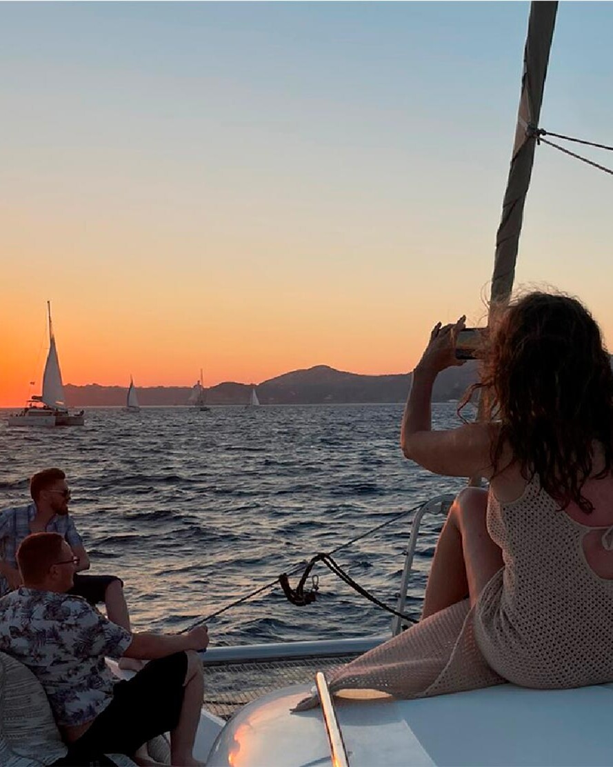 Travellers on catamaran in Santorini taking photos of the sunset in the caldera