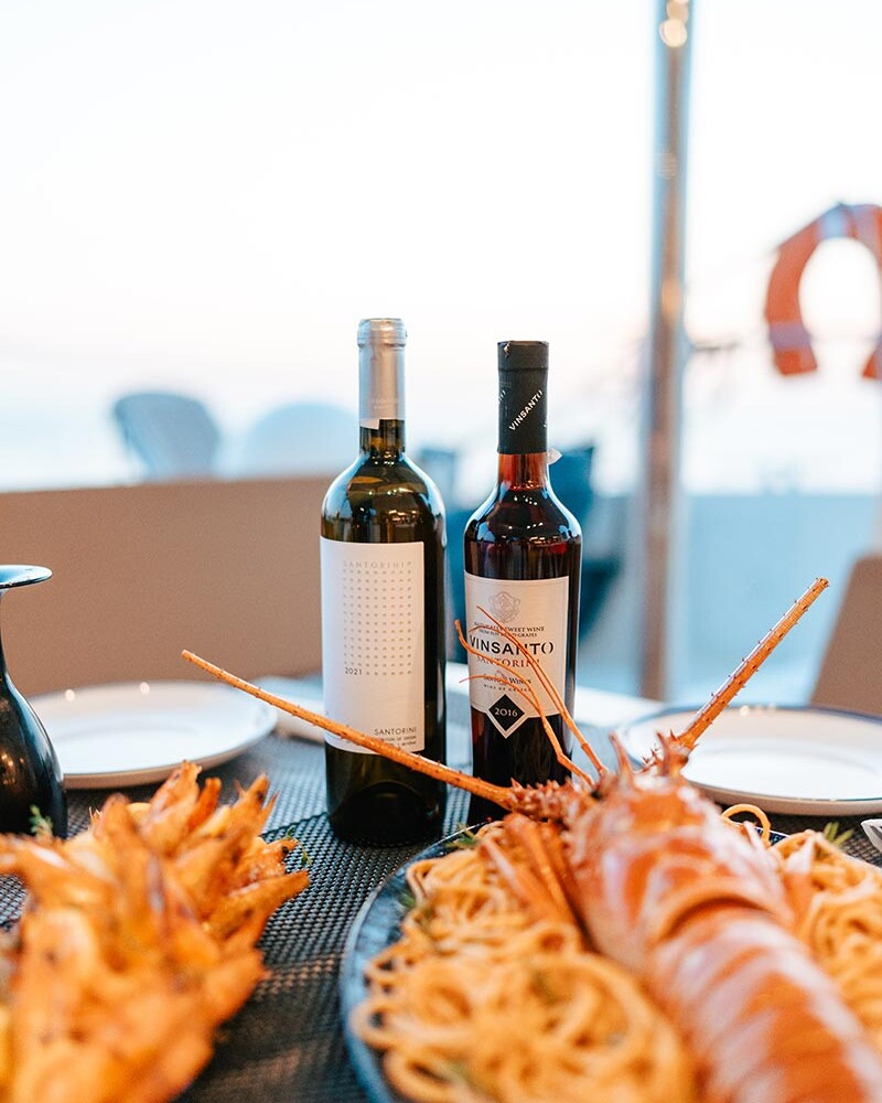 Wine, food and lobster on a table on a catamaran in Santorini